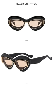 Detail of cat eye sunglasses with black frames, light tea lenses and gold metal trim