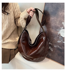 Close-up of high-gloss coffee brown PU leather shoulder bag with wide strap detail