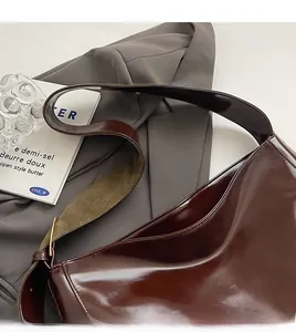 Detail of deep brown glossy PU leather tote bag with wide shoulder strap and metal buckle
