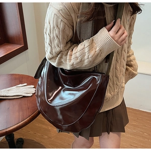 Detailed view of dark brown glossy patent leather half-moon shoulder bag with flap closure