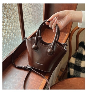 Detail view of dark brown glossy bucket bag with ball clasp and Rioa & Luxury branding