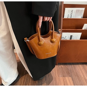 Detail of luxury brown bucket bag with Rica & Luxury logo and stylish round ball handles