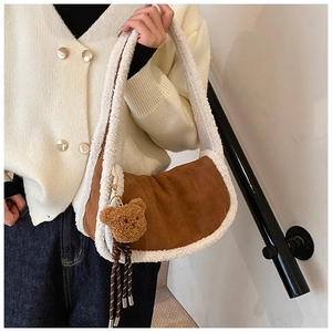 Detail von flauschigem Teddyfell-Besatz und Bärenanhänger an brauner Wildledertasche