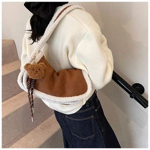 Detail der braunen Wildledertasche mit weißem Pelzbesatz und süßem Bärenanhänger