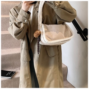 Detailaufnahme der beige Fleecetasche mit Bärenanhänger über einem khakifarbenen Mantel