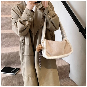 Detail der beigen Cord-Schultertasche mit Pelzbesatz und braunem Bärenanhänger