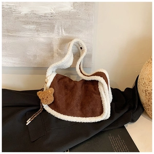 Details einer dunkelbraunen Tasche aus Wildlederimitat mit Teddybär-Anhänger und Lammfell