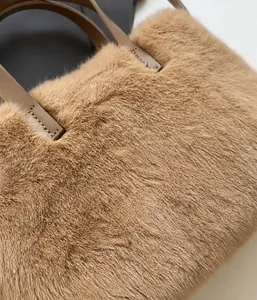 Détail de la texture douce en fausse fourrure camel et de l'anse en cuir de ce sac à main