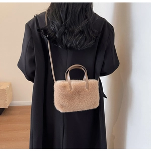 Gros plan du sac à main en peluche marron clair avec des poignées en cuir sur un blazer