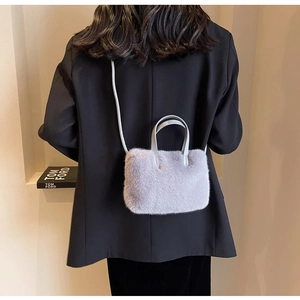 Détail d'un sac à main en peluche lavande avec poignée en cuir sur un blazer noir chic