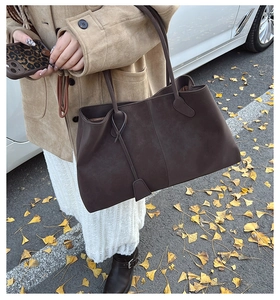 Detail of a large brown suede tote bag with slim shoulder straps in an autumn setting