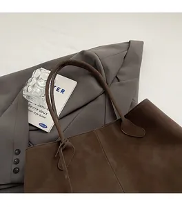 Detail view of large dark brown suede tote bag featuring minimalist stitching and soft straps