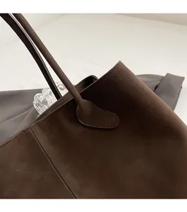 Close-up of fine stitching and matte suede texture on a coffee brown tote bag handle