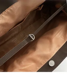 Detail of dark brown tote bag interior featuring patterned lining and silver magnetic buckle