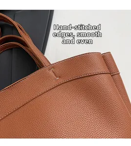 Detail of caramel brown lychee leather tote with white stitching and smooth edges