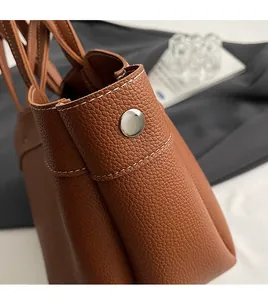 Detailed view of dark brown lychee grain leather with contrast stitching and silver buckle
