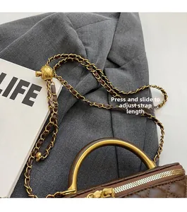 Detail der braun gesteppten Tasche mit goldener Kugelschnalle und Kettenriemen