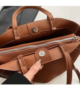 Detailed interior of brown pebbled leather tote showing multi-layer compartments and zippers