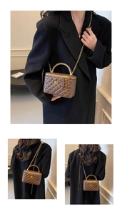 Detail of brown quilted leather bag with gold curved handle and floral emblem