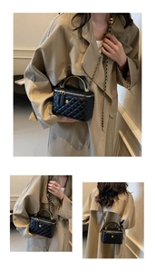 Detail of black quilted box bag with gold metal handle and camellia floral buckle