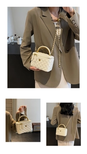 Detail of white quilted crossbody bag with golden camellia ornament and chain strap