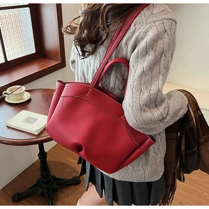 Detail of red lychee leather tote bag with white contrast stitching and shoulder strap
