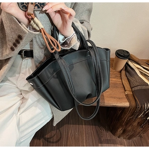 Close-up of black lychee grain leather tote bag with white contrast stitching details