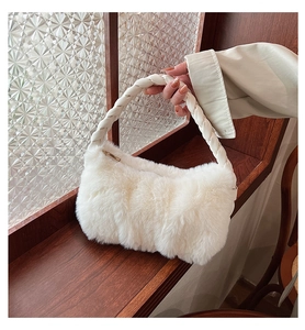 Close-up of a white plush handbag featuring a woven braided handle and gold zipper