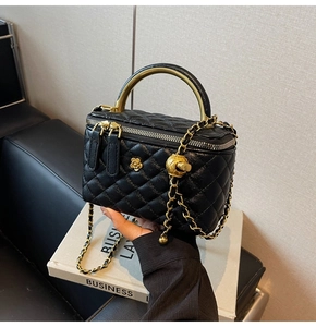 Detail einer schwarzen gesteppten Kosmetiktasche mit Goldgriff und Metallkettenriemen