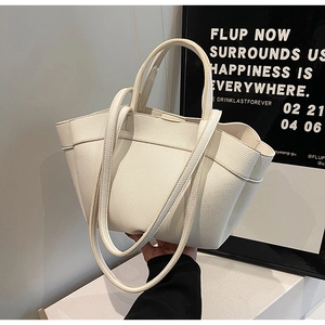 Close-up of off-white lychee leather tote bag featuring dual handles and soft texture
