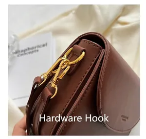 Detailed close-up of premium golden metal D-ring hardware on a brown leather shoulder bag