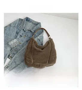Detailed view of brown plush tote bag with dark leather handles and gold metal rings