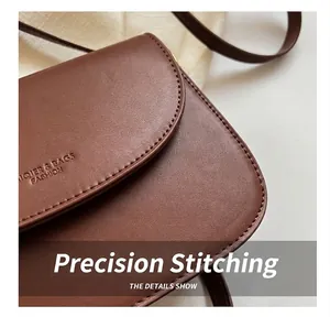 Detailed view of neat stitching and embossed logo on minimalist brown leather crossbody bag