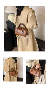 Detail view of a vintage brown Boston bag featuring fine leather texture and twin handles