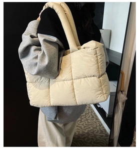 Detail view of large quilted puffer tote bag in cream nylon fabric with soft handles