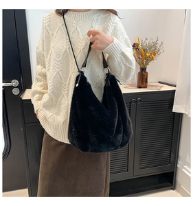 Furry black plush hobo bag with a leather strap and gold metal rings shown on model