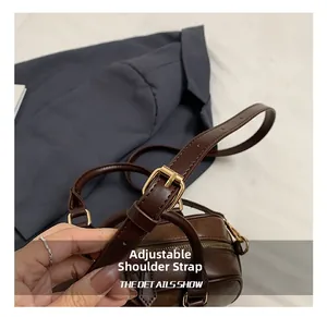 Detail of adjustable shoulder strap with gold buckle on dark brown retro handbag
