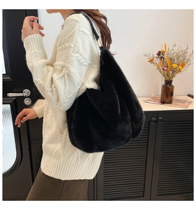 Detail of soft black faux fur tote bag with leather strap on a model shoulder