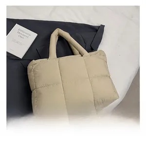 Close-up of beige quilted tote bag with padded handles and square stitching detail