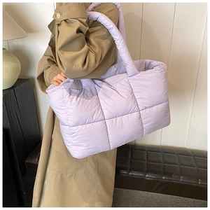 Detail van gewatteerde lavendel puffer draagtas met dikke handvatten gedragen door model