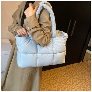 Close-up of light blue quilted tote bag made of lightweight fabric on female model