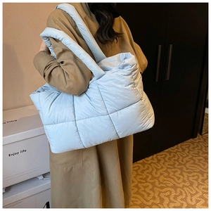 Close-up of light blue quilted tote bag with padded straps and soft down texture