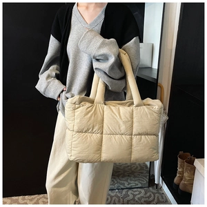 Detail of a large cream quilted shoulder bag with soft padding and wide handles