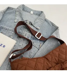 Detail der braunen Stepptasche mit verstellbarem Gurt und Rautenmuster auf Denim