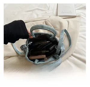 Detail showing internal capacity of light blue textured mini bag with everyday items