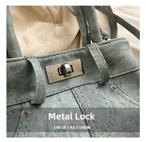 Detail of light blue denim bag featuring silver metal twist lock and contrast stitching