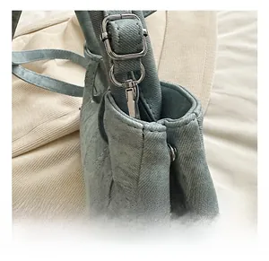 Detail of silver metal hook and adjustable buckle on blue denim shoulder bag strap