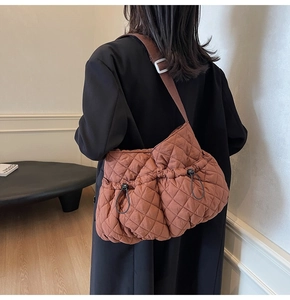 Detail of rust brown quilted tote bag on model showing large capacity and soft texture