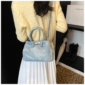 Model wearing a light blue denim handbag with silver lock and studs in a daily setting
