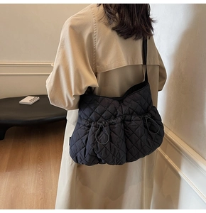 Detail of black quilted nylon tote bag with drawstring features and adjustable strap